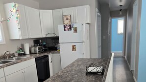 Eine Küche mit weißen Schränken, einer Arbeitsplatte aus Granit und einem Kühlschrank mit Fotos.