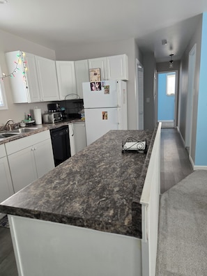 Eine Küche mit weißen Schränken, einer Arbeitsplatte aus Granit und einem Kühlschrank mit Fotos.