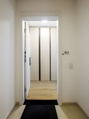 A hallway with a black mat leading to a door marked with the number 311. - Z Pinheiros  (São Paulo)
