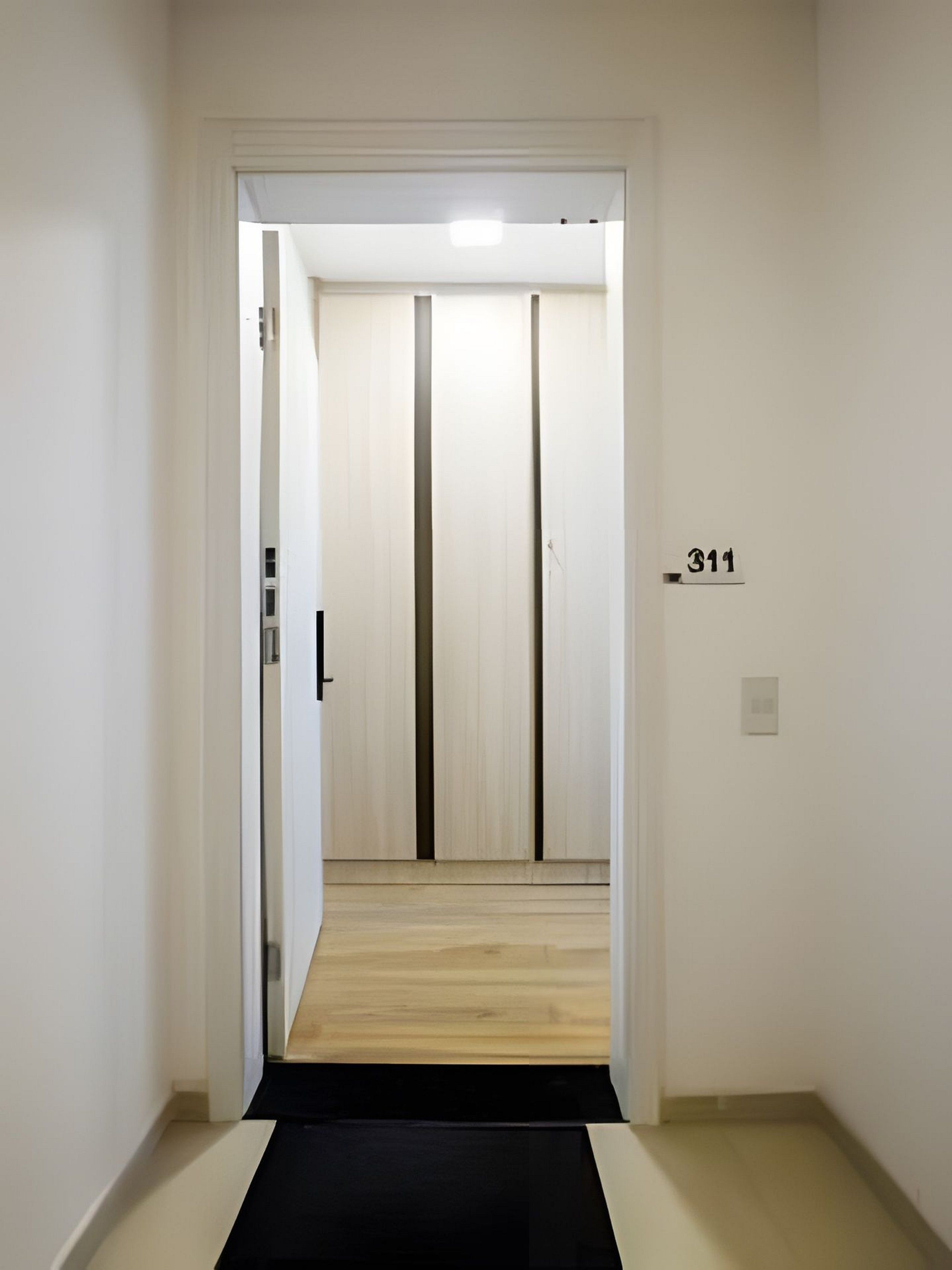 Un pasillo con un tapete negro que lleva a una puerta con el número 311.