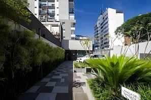 A pathway leading to a building with a modern design, surrounded by greenery and a clear sky. - Z Pinheiros  (São Paulo)