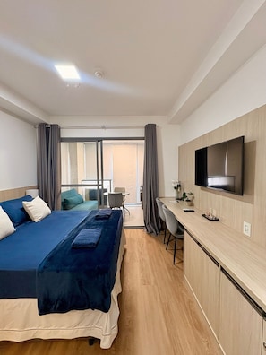 A hotel room with a bed, a desk, a television, and a view of the outside. - Z Pinheiros  (São Paulo)