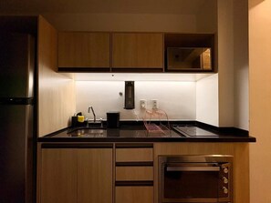 A compact kitchen with wooden cabinets, a built-in microwave, and a stainless steel range hood. - Z Pinheiros  (São Paulo)