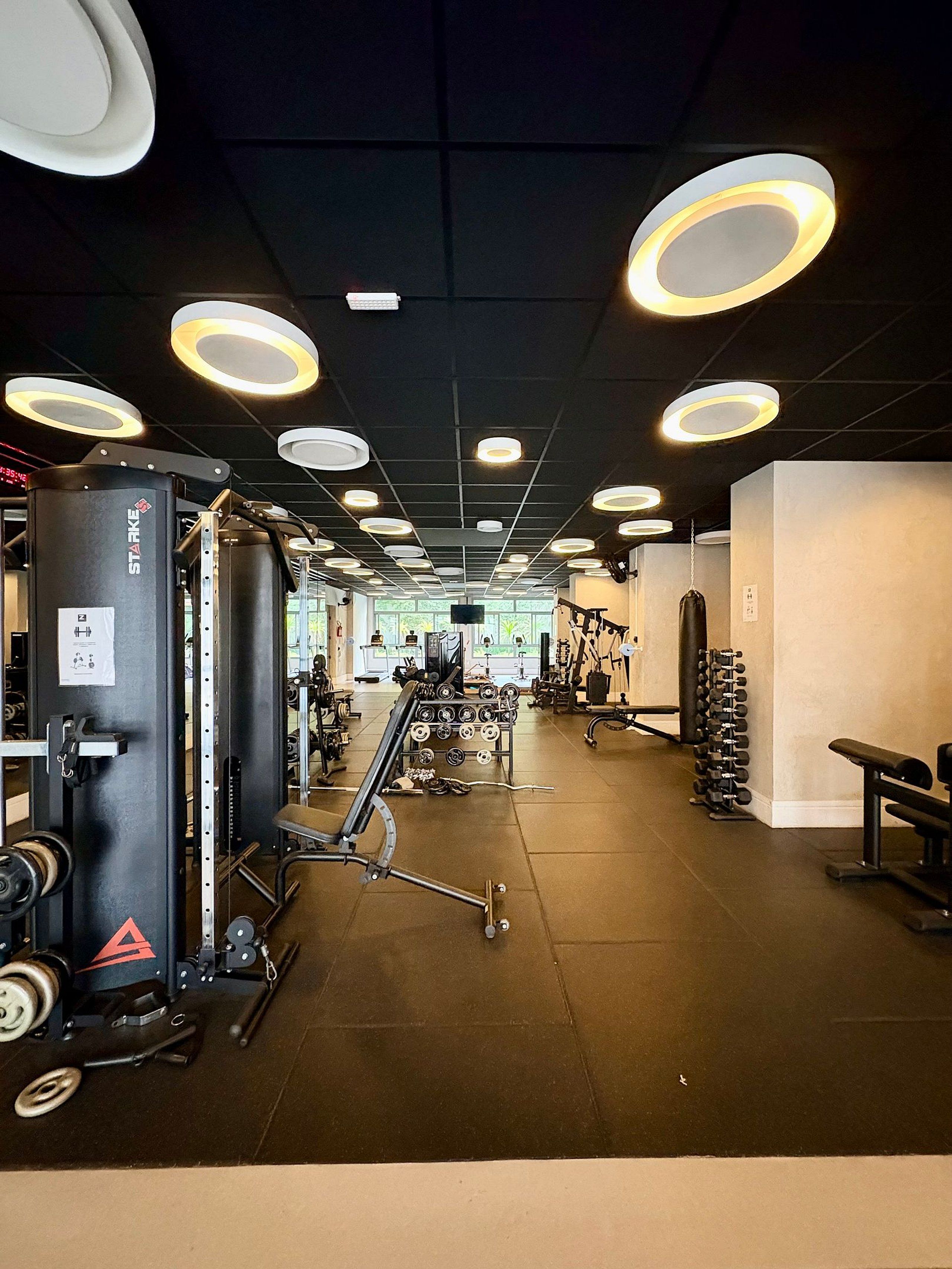 Une salle de sport équipée de divers appareils d’entraînement, notamment une machine Smith, des poids libres et un banc.