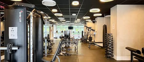 Une salle de sport équipée de divers appareils d’entraînement, notamment une machine Smith, des poids libres et un banc.