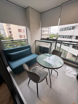A balcony with a sofa, a glass table, and chairs. - Z Pinheiros  (São Paulo)