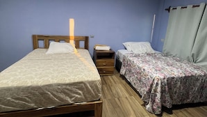 Quarto com duas camas, piso de madeira e mesa de cabeceira.