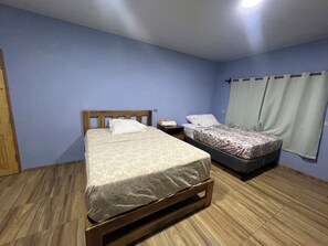 Un dormitorio con dos camas, cabeceros de madera, una mesita de noche y una ventana con cortinas.