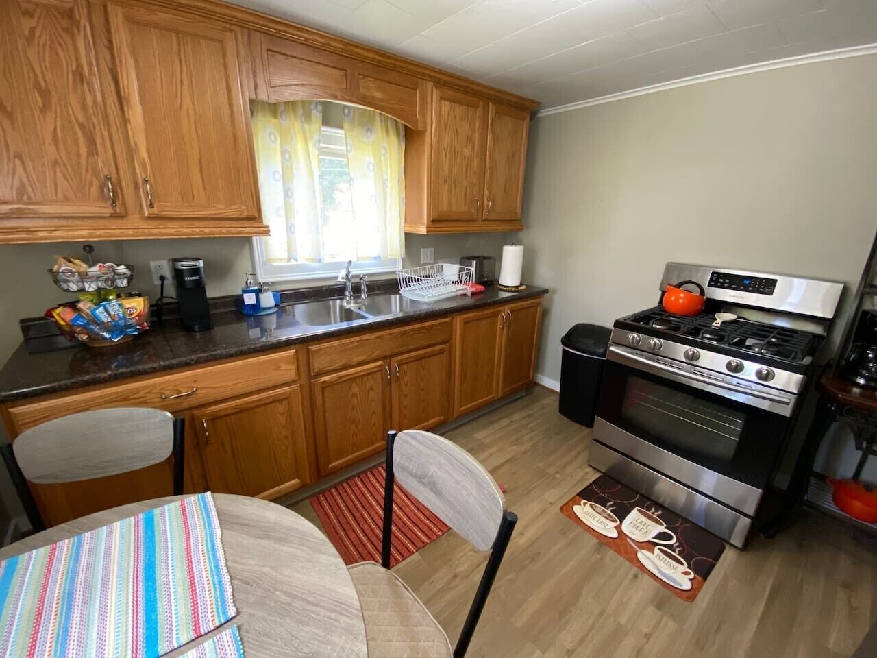 Une cuisine avec des meubles en bois, une cuisinière en acier inoxydable et une table à manger avec des chaises.