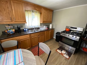 Une cuisine avec des meubles en bois, une cuisinière en acier inoxydable et une table à manger avec des chaises.