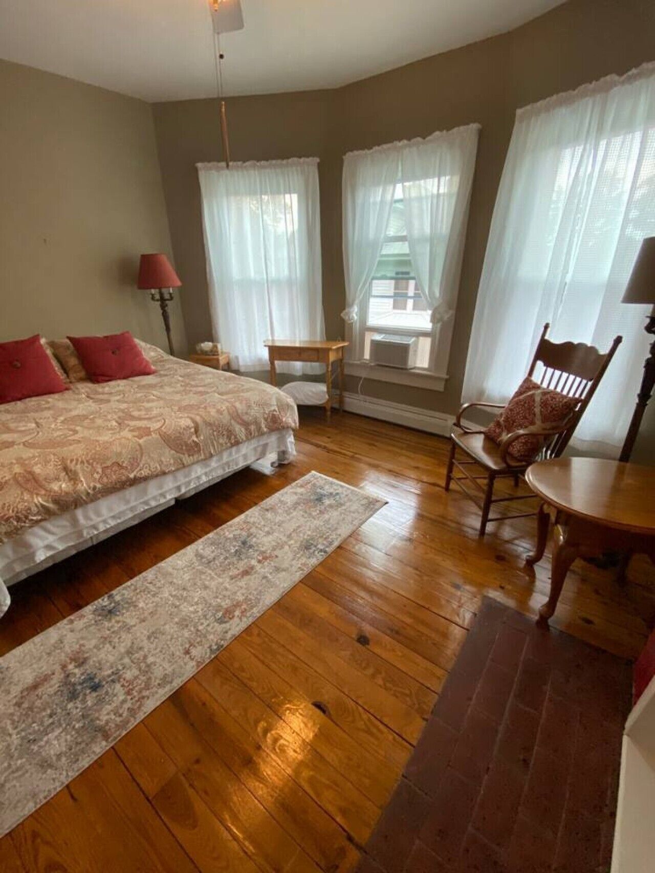 Une chambre à coucher avec un lit, une chaise, une table et une fenêtre avec des rideaux.