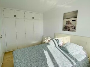 A bedroom with a bed, a wardrobe, and a painting on the wall. - Apartment in Salou, 2 minutes from the beach (Salou)