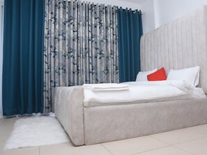 Quarto moderno com uma cama grande, uma cabeceira e um tapete branco.