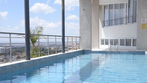 An indoor swimming pool with a view of the cityscape. - Imagine Luxury- 2 Bedroom (Nairobi)