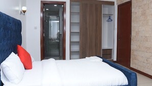 A bedroom with a bed, a wardrobe, and a bathroom. - Imagine Luxury- 2 Bedroom (Nairobi)