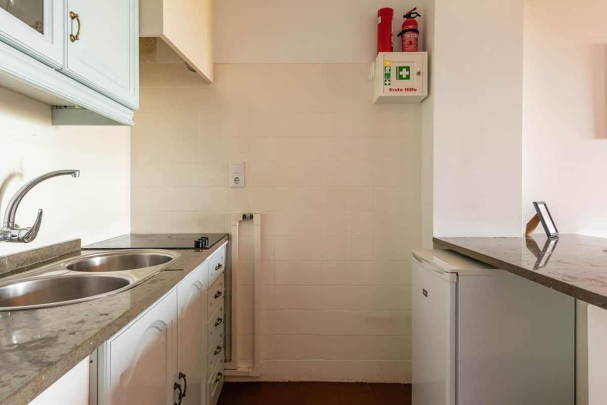 A compact kitchen with two stainless steel sinks, a white refrigerator, and a white cabinet with a handle.