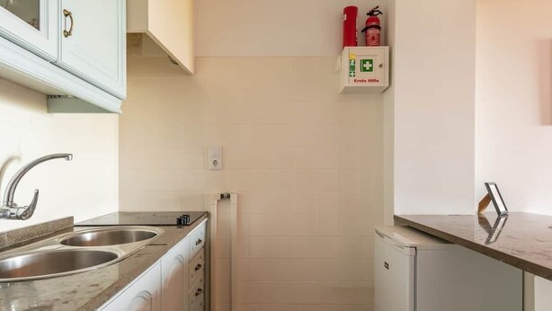A compact kitchen with two stainless steel sinks, a white refrigerator, and a white cabinet with a handle. - River View Studio Alfama (Lisbon)