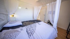 A bedroom with a canopy bed, a bedside table, and a wall-mounted lamp. - Villa Zenitude—Indoor Pool, Jacuzzi, and Sauna (Jezainville)