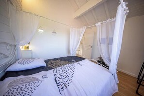 Ein Schlafzimmer mit Himmelbett, Nachttisch und Wandleuchte.