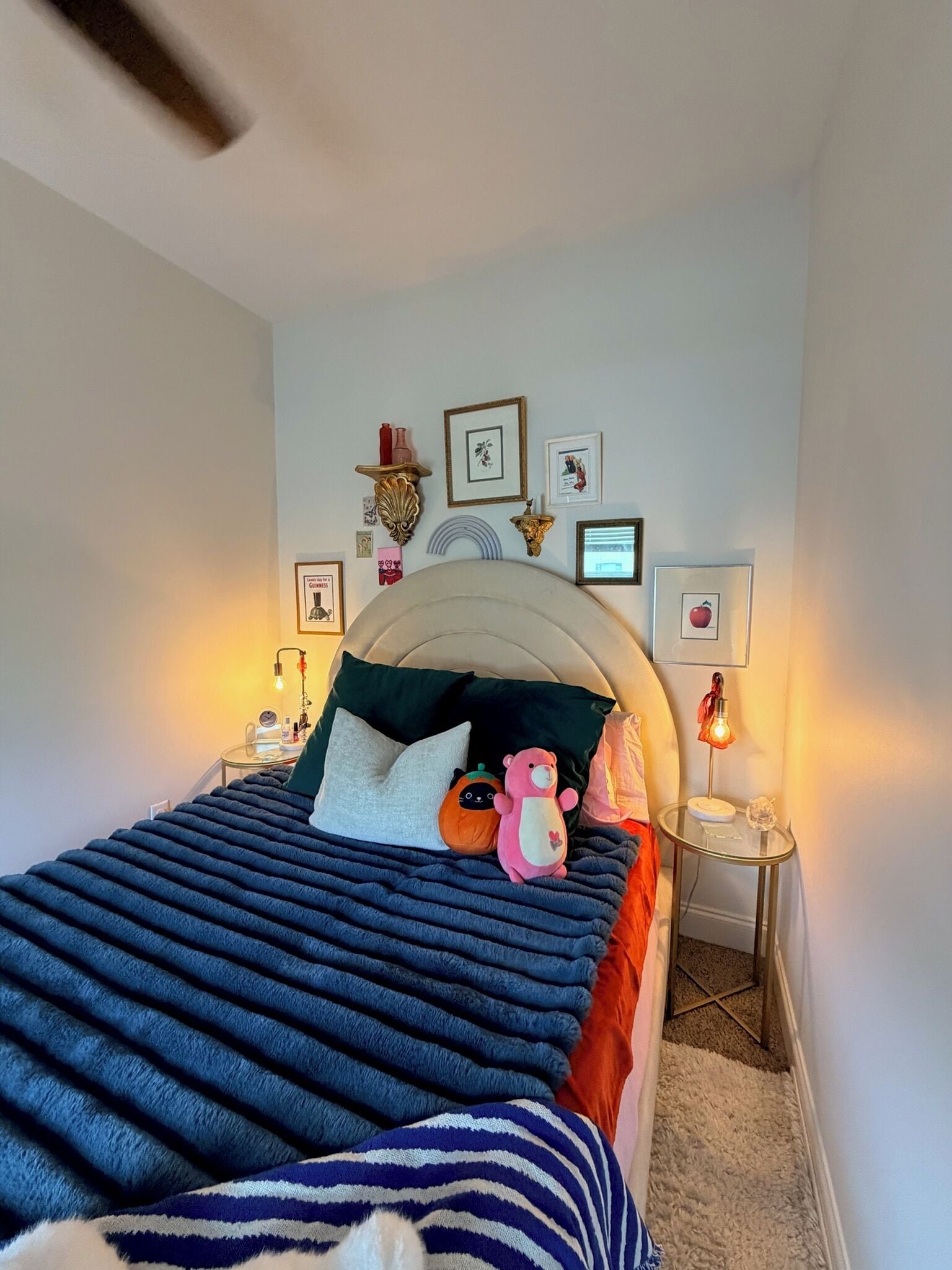 Un dormitorio con cama, almohadas, un osito de peluche y adornos en la pared.