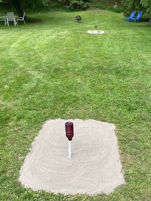 A lawn with a circular area marked for a game, a chair, and a small table. - Rushford Lakeside Family Getaway (Houghton)