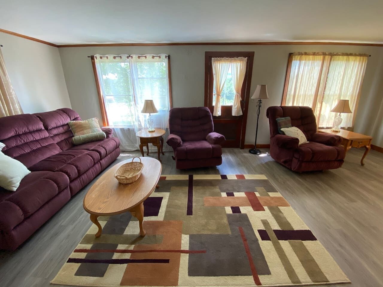 Un salon avec un canapé, des fauteuils, une table basse et un tapis.
