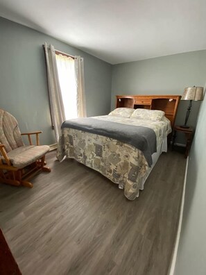 A bedroom with a bed, a chair, and a nightstand. - Rushford Lakeside Family Getaway (Houghton)