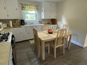 A compact kitchen with a dining table, chairs, and a stove. - Rushford Lakeside Family Getaway (Houghton)