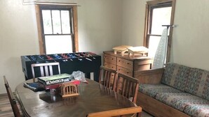 Un comedor con una mesa y sillas de madera, una mesa de fútbol de mesa y un sofá.