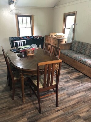 A dining area with a wooden table and chairs, a foosball table, and a sofa. - Rushford Lakeside Family Getaway (Houghton)