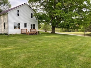 A white house with a porch and a large tree in front. - Rushford Lakeside Family Getaway (Houghton)