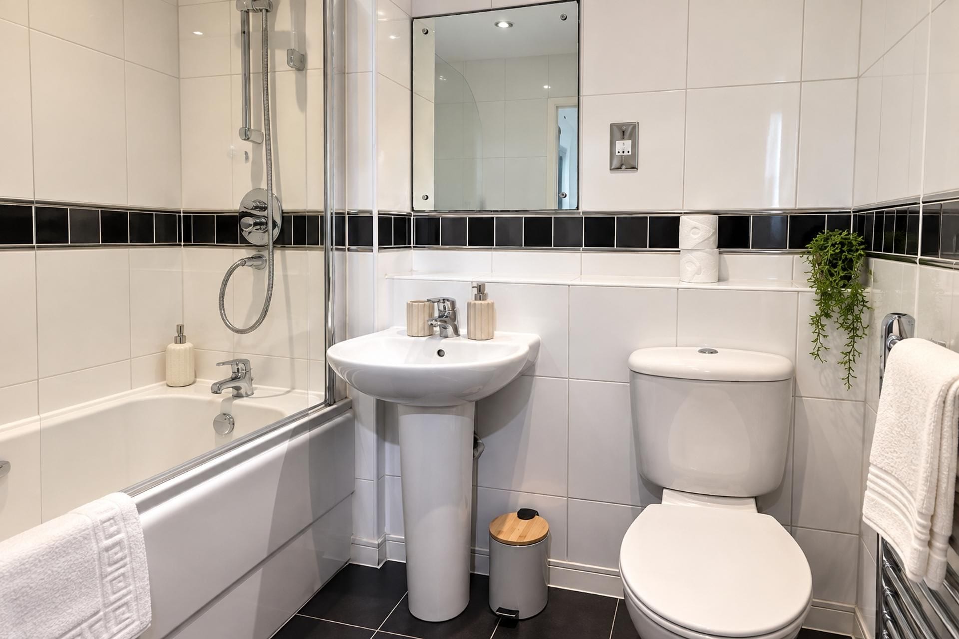 Ein modernes Badezimmer mit einer Badewanne, einem Waschbecken, einer Toilette und einem Spiegel.