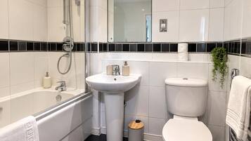 Ein modernes Badezimmer mit einer Badewanne, einem Waschbecken, einer Toilette und einem Spiegel.