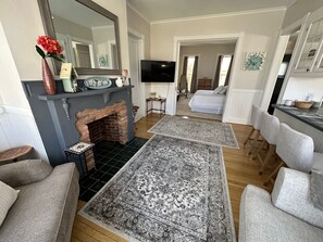 Un salon avec une cheminée, un téléviseur et un coin repas avec des chaises.
