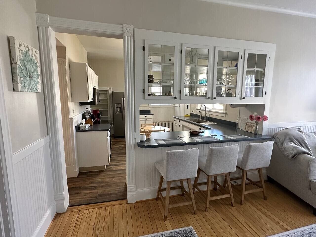 A kitchen with a central island, white cabinetry, and a grey sofa in the adjacent living area.