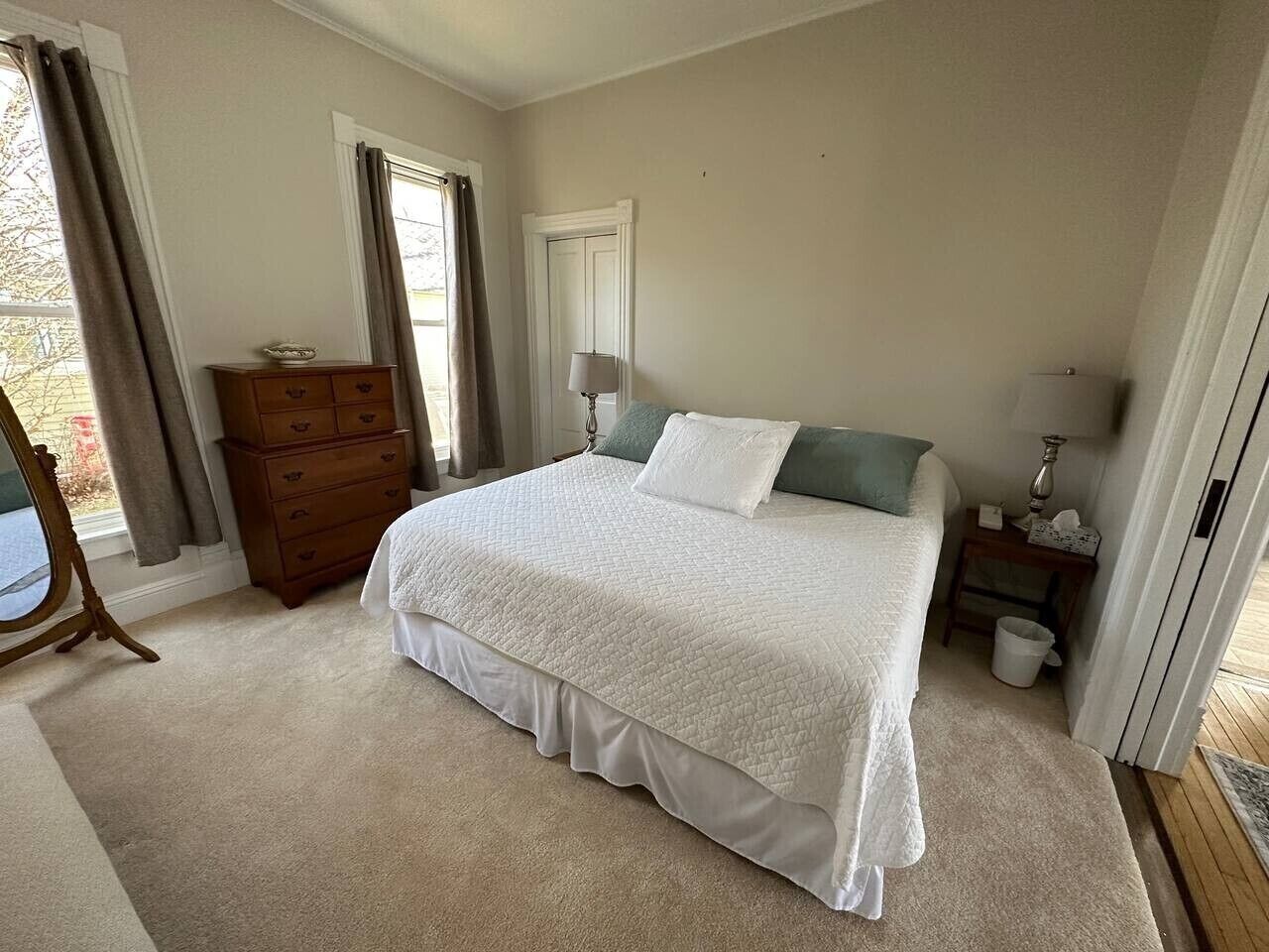 Une chambre à coucher avec un lit, une commode et une fenêtre avec des rideaux.