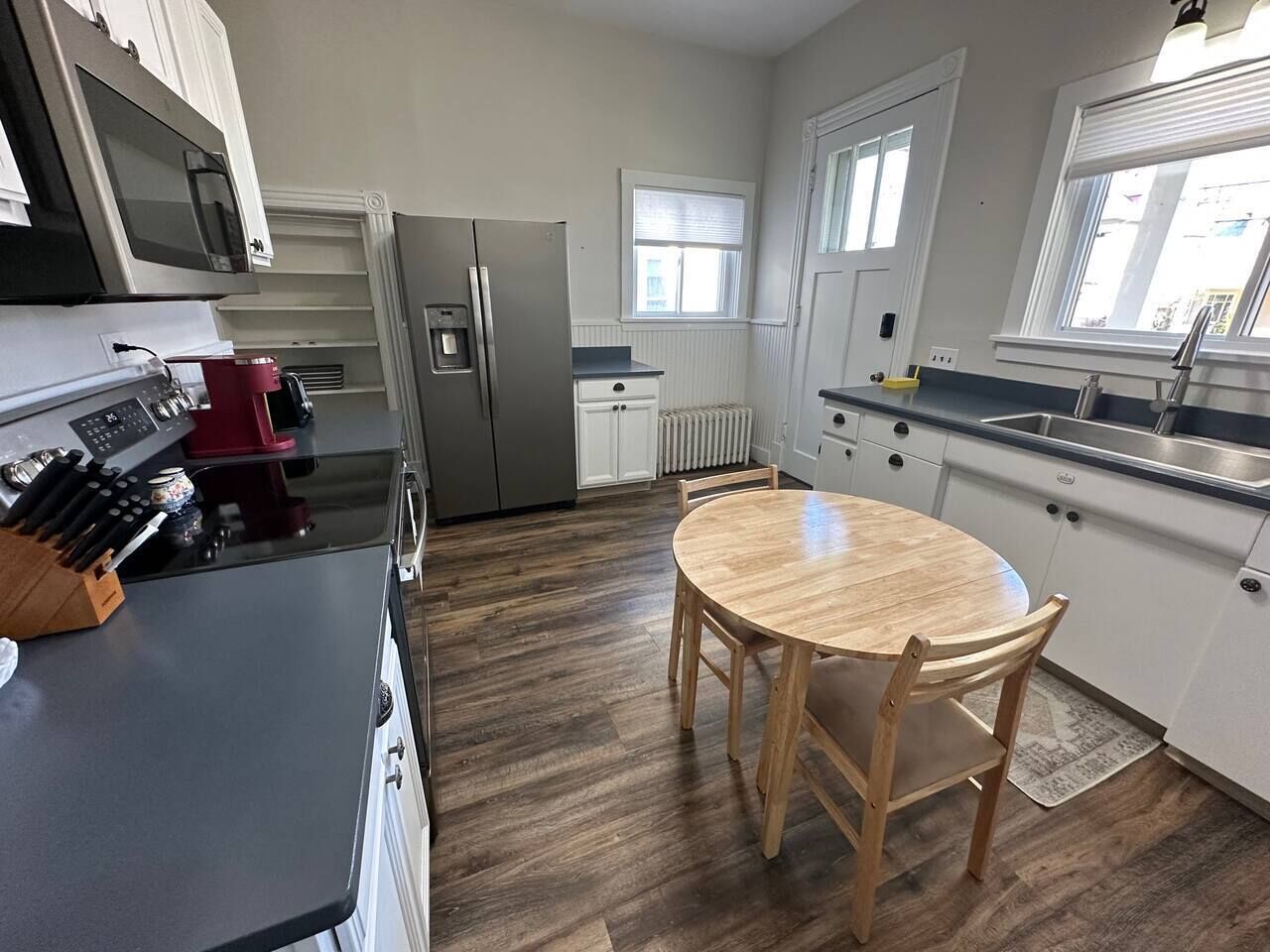 Une cuisine équipée d’un four à micro-ondes, d’une cuisinière, d’un réfrigérateur et d’une table ronde en bois, ainsi que de chaises.
