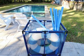 Zona junto a la piscina con piscina, sillas de descanso y un box para guardar flotadores azules.