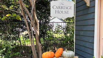 A sign reading 'The Carriage House' with pumpkins and hay bales in front.