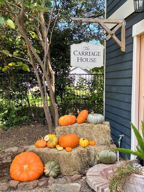 Un letrero que dice 'The Carriage House', con calabazas y pacas de heno al frente.