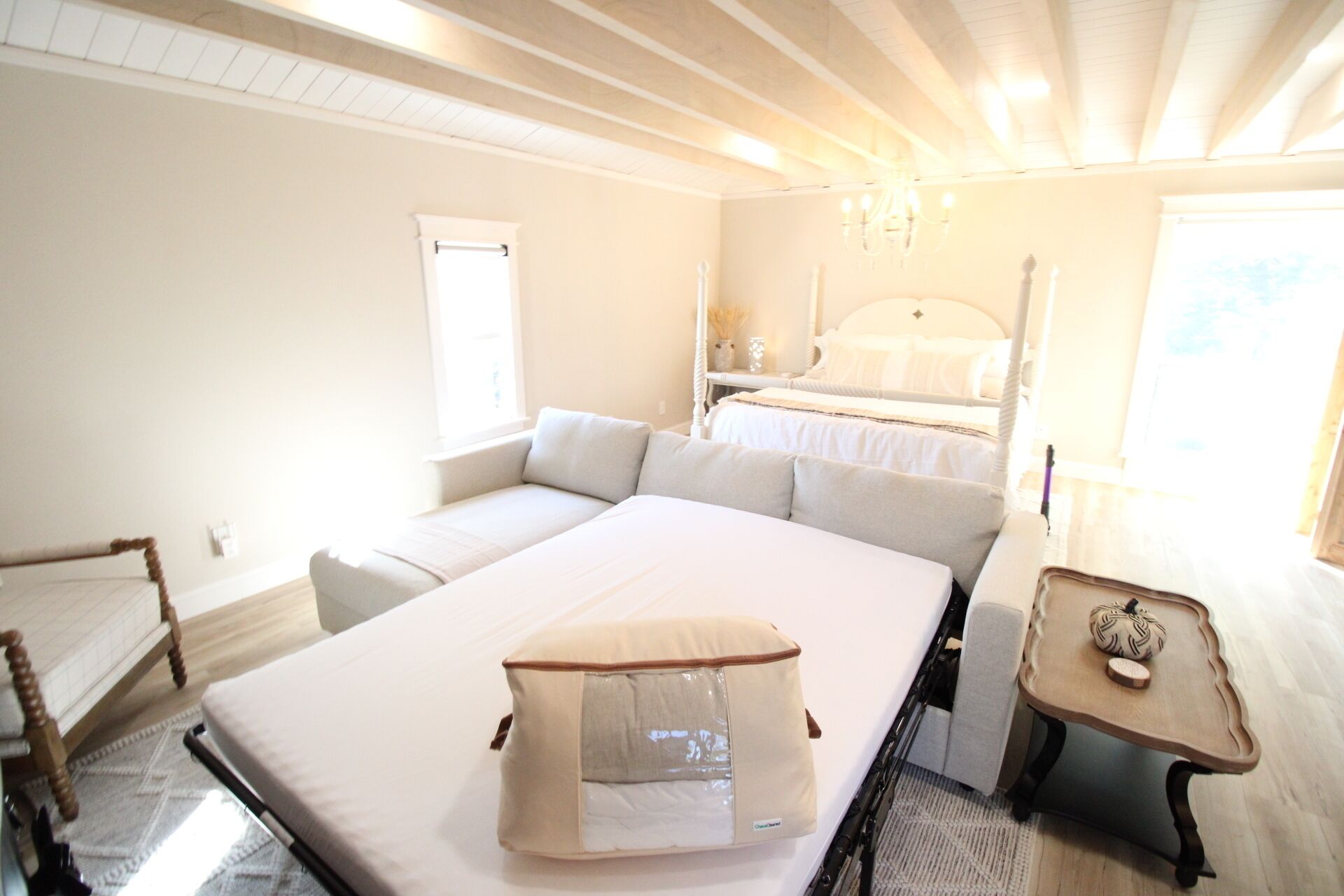 Un dormitorio con una cama grande, una mesita de noche, una silla y una ventana.