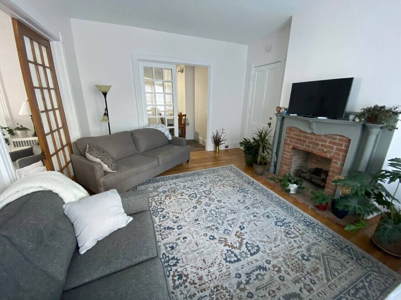 A living room with a sofa, a patterned rug, a fireplace, and a TV.