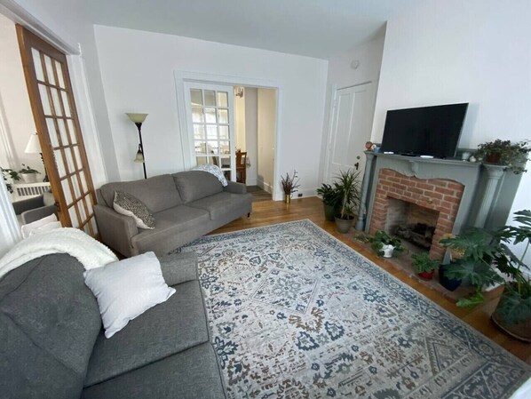 A living room with a sofa, a patterned rug, a fireplace, and a TV.