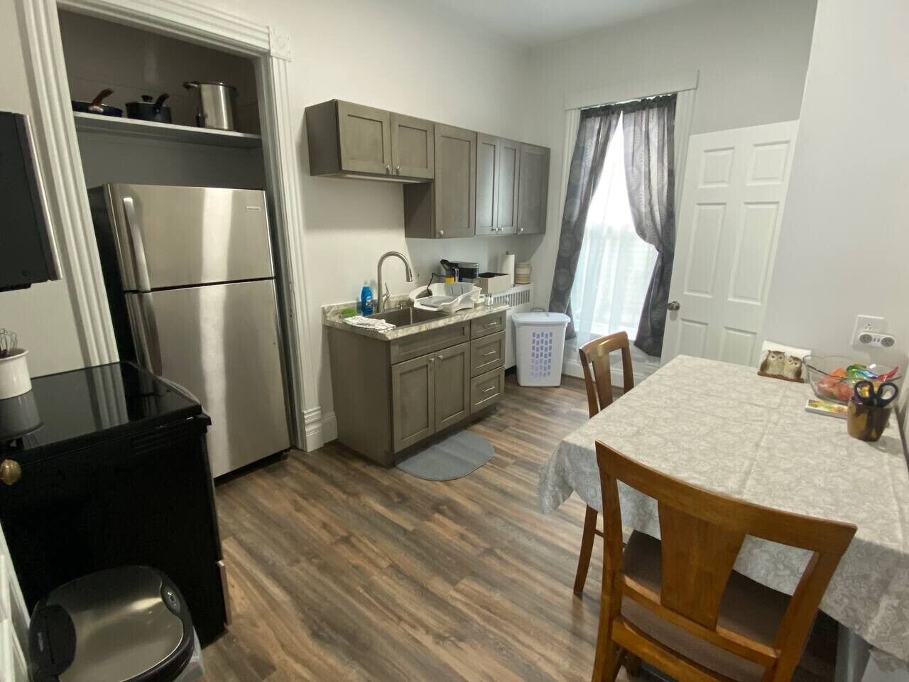 A compact kitchen with a refrigerator, stove, and sink. There is a dining table with chairs.