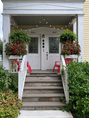 A two-story house with a front porch, two doors, and a staircase leading to the entrance.