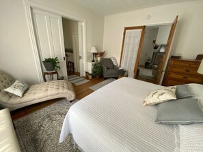 Un dormitorio con cama, sofá, sillón, cómoda y espejo.