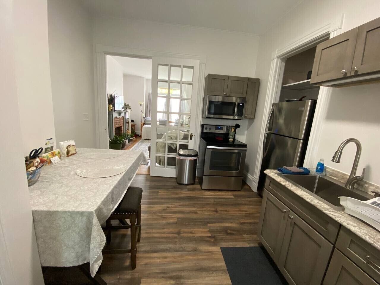 Une cuisine compacte avec un coin repas, des appareils en acier inoxydable et une vue sur le salon.