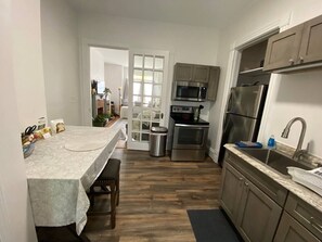 A compact kitchen with a dining area, stainless steel appliances, and a view into the living room.