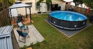 An above-ground swimming pool with a patio area, a covered seating area, and a fenced yard. - 4-bedroom Pool house in serene Hollywood with cool AC breeze (Hollywood)