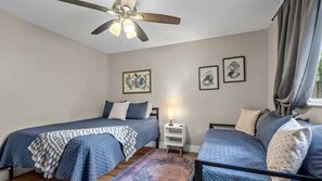 Ein Schlafzimmer mit zwei Betten, einem Deckenventilator und Kunstwerken an den Wänden.